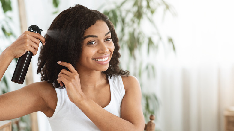 Woman smiling and spraying product on hair