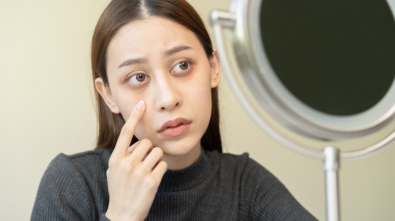 Woman look at puffy eyes in mirror