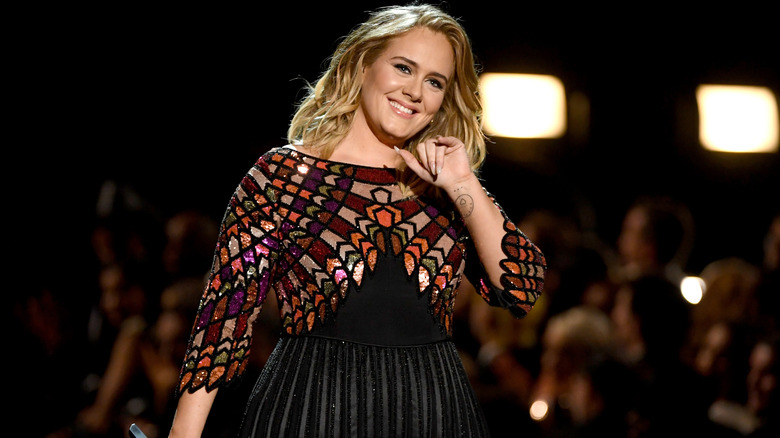 Adele cheesing for a camera while holding a microphone 