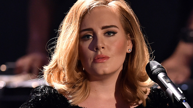 Adele looking serious behind a microphone