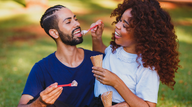 laughing couple eating ice cream in a park