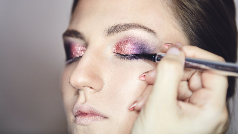 Artist applying glittery eye makeup