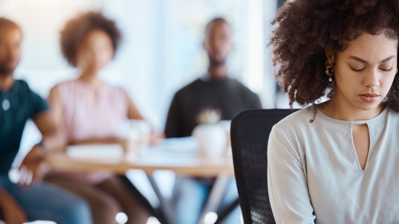 Woman sitting alone in front of people