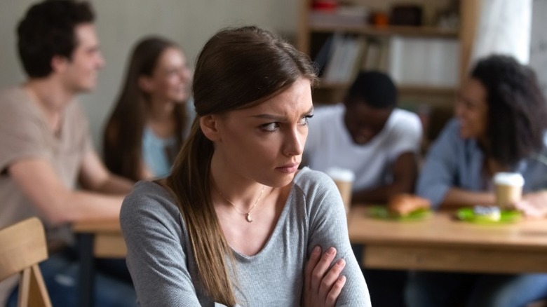 Woman sitting away from group of people