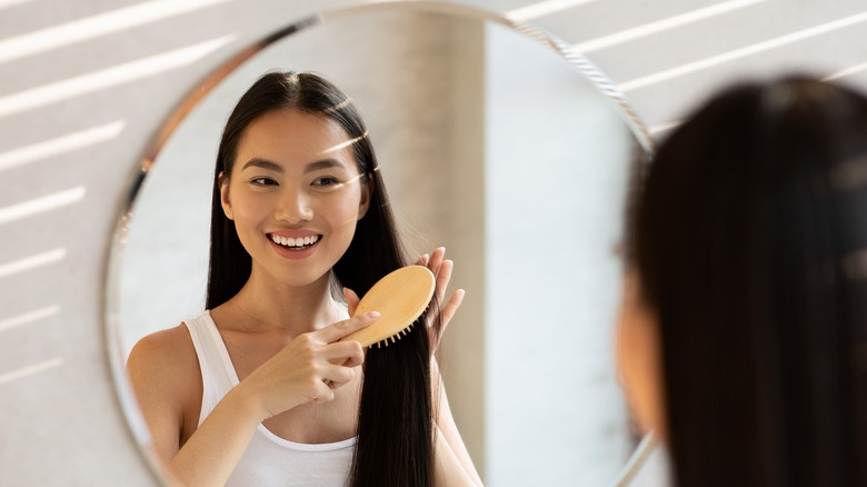 Girl brushing hair in mirror