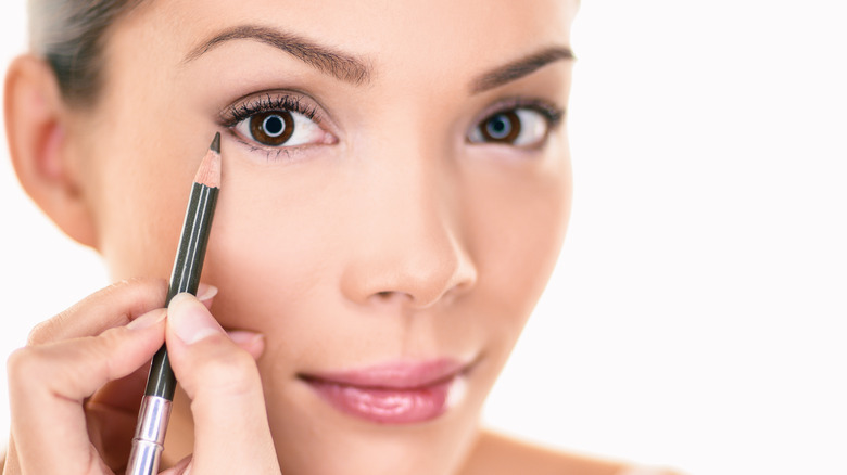 Woman applying brown eyeliner