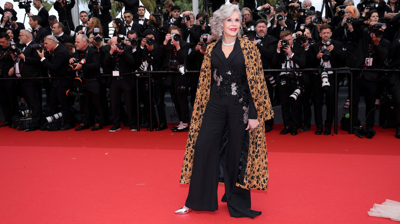 Jane Fonda standing on Cannes Film Festival red carpet in front of photographers