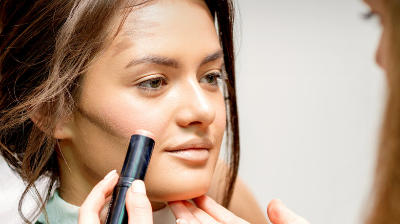 Makeup artist applying cream blush to woman's cheeks