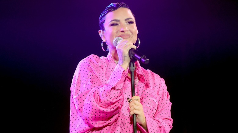 Demi Lovato smiling, holding microphone