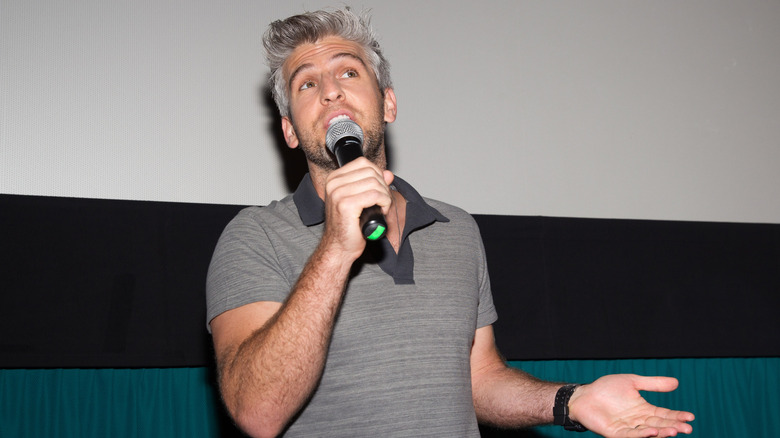 Max Joseph addressing an audience with a microphone in his hand