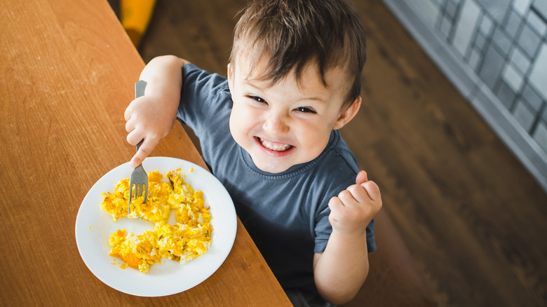 child smiling with scrambled eggs