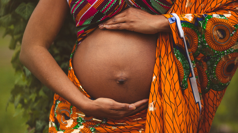 Pregnant person draped in African fabric