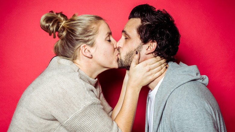 Couple kissing against red background