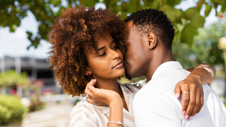 man kissing woman's cheek