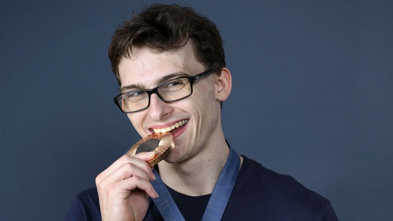 Stephen Nedoroscik smiling and biting his bronze Olympic medal