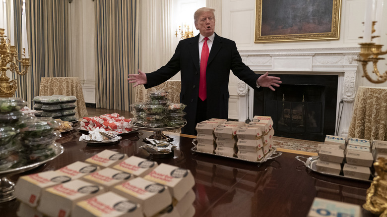 Donald Trump standing behind table full of fast food platters