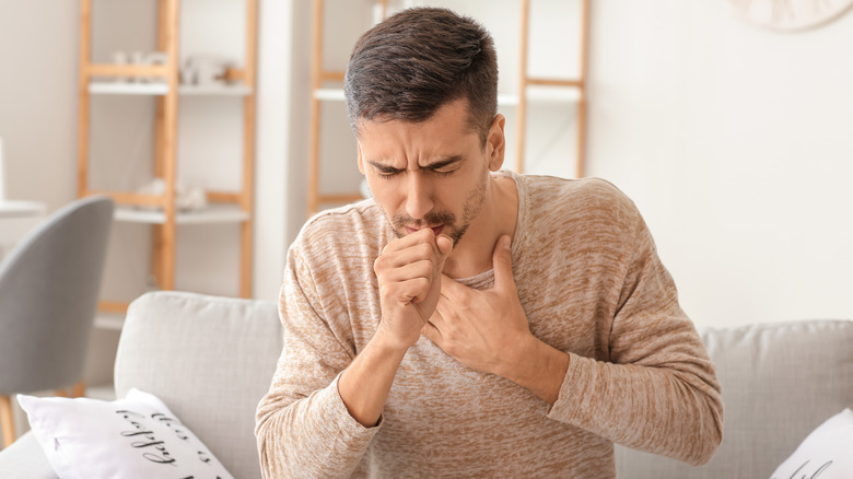 man coughing on a couch