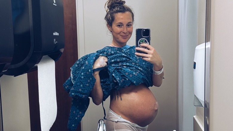 Alexa PenaVega smiling in mirror, baby bump visible