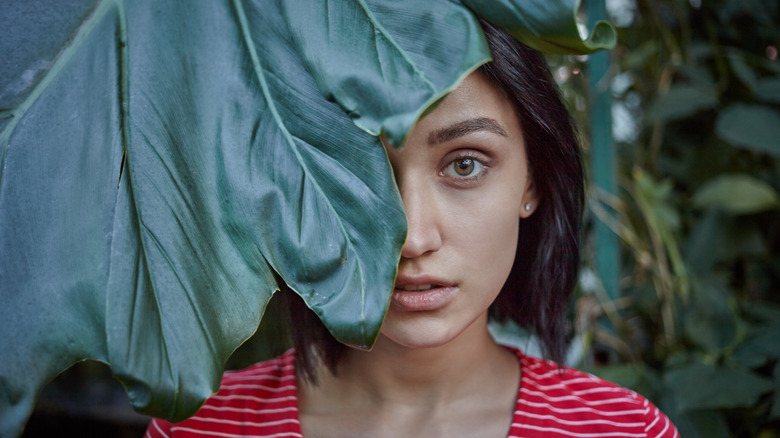 woman behind large leaf