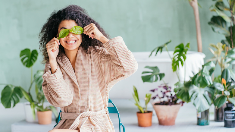 woman holding leaves over eyes