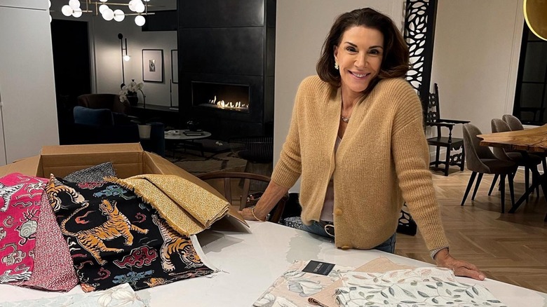 Hilary Farr posing behind a counter full of fabric samples