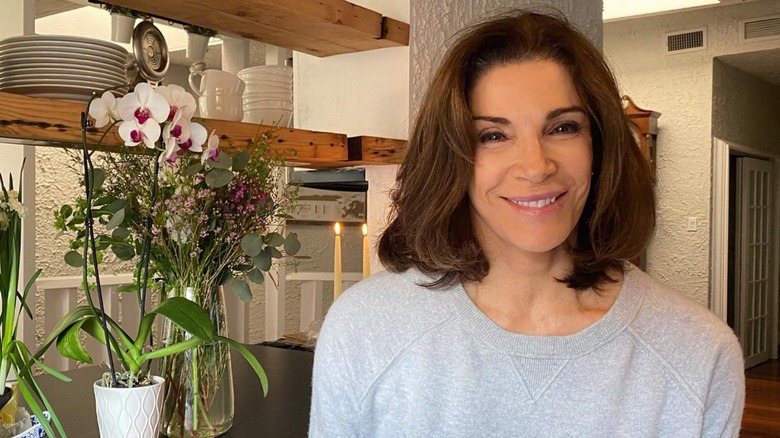 Hilary Farr smiling next to two flower arrangements 