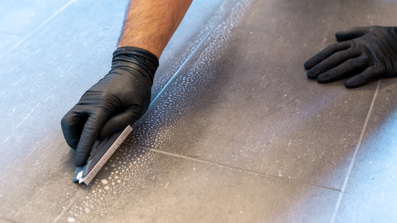 hands cleaning grout with brush