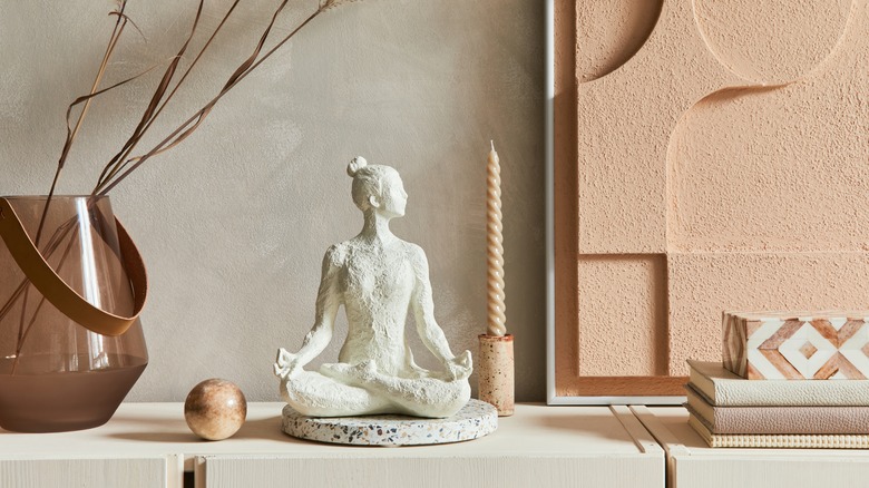 Meditation sculpture next to tan 3D art 