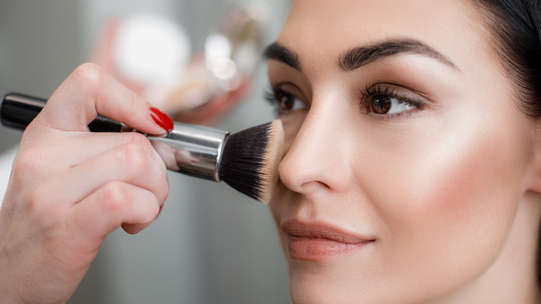 A makeup brush on a woman's face 