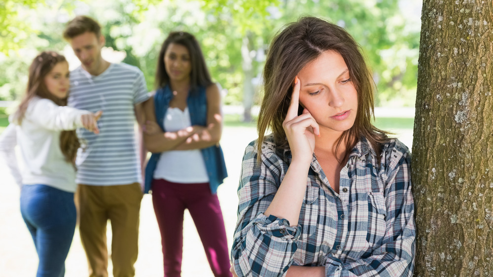 Woman alone with group in background