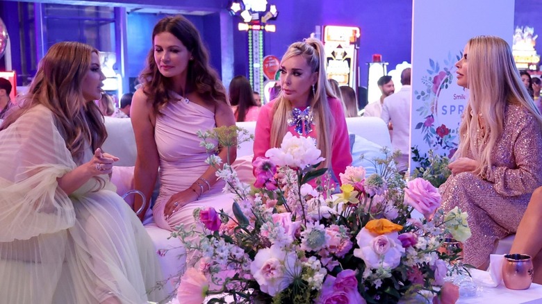 Real Housewives of Miami talking behind flower arrangement