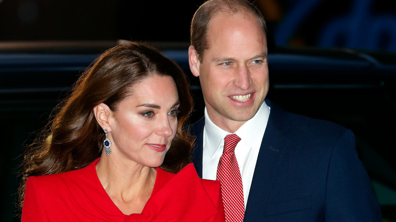 Kate Middleton stands in front of Prince William