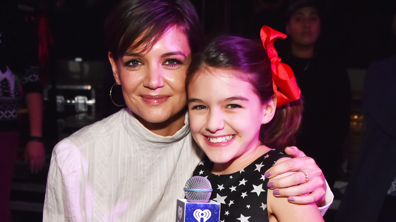 Katie Holmes and Suri Cruise pose, Suri holding mic 