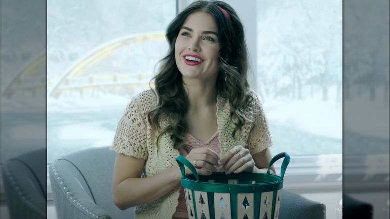 Michelle Randolph with dark hair and red lips holding a basket in "Snow White Christmas" (2018)