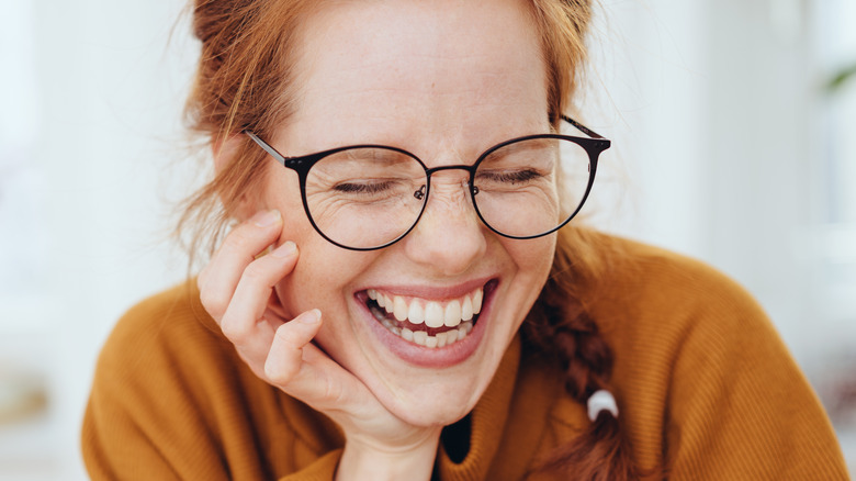 Red haired woman in glasses laughing