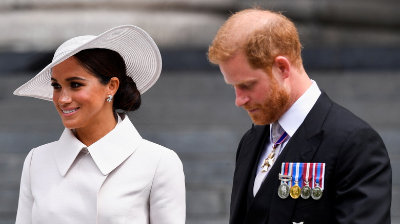 Prince Harry looks down as Meghan Markle smiles