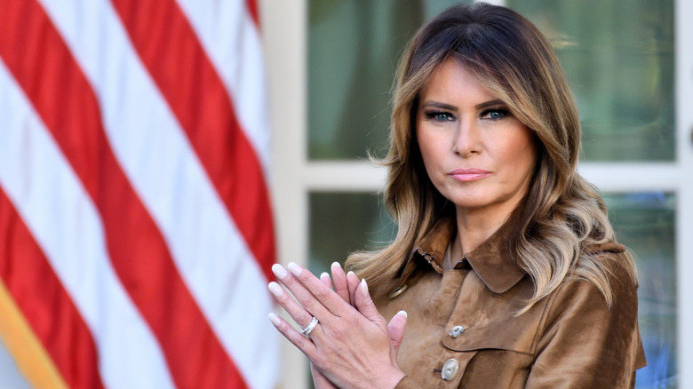 Melania Trump applauding in brown coat at White House