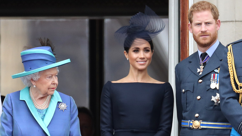 Queen Elizabeth II standing beside Meghan Markle and Prince Harry