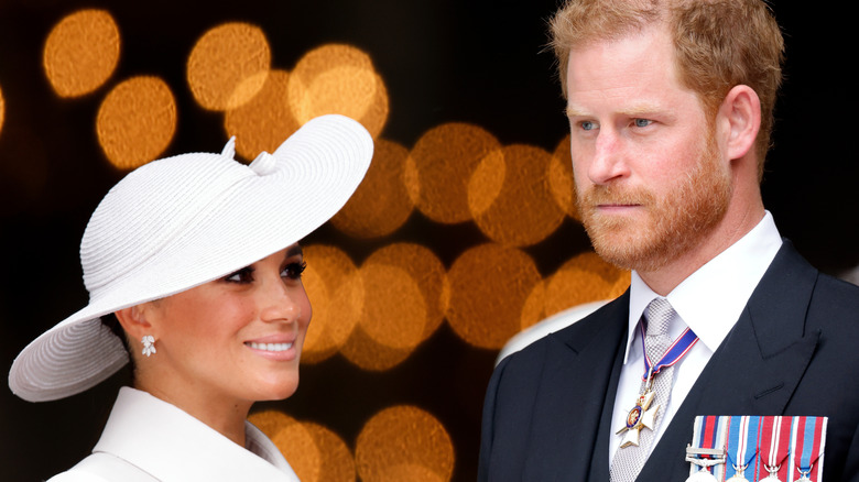 Meghan Markle smiling in a white hat while Prince Harry grimaces