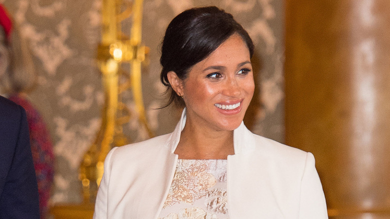 Meghan Markle smiling in white coat