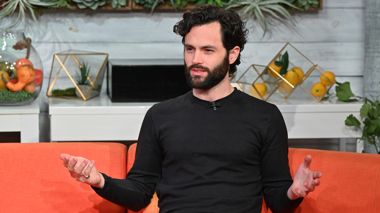 Penn Badgley speaking with hands open.