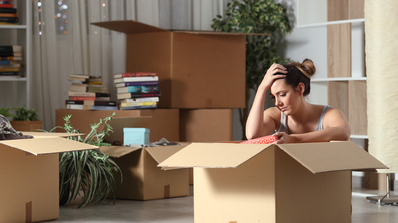 Sad woman packing up her belongings in boxes