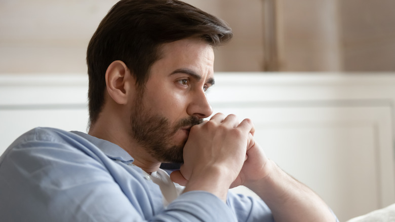 Worried man looking contemplative with folded hands