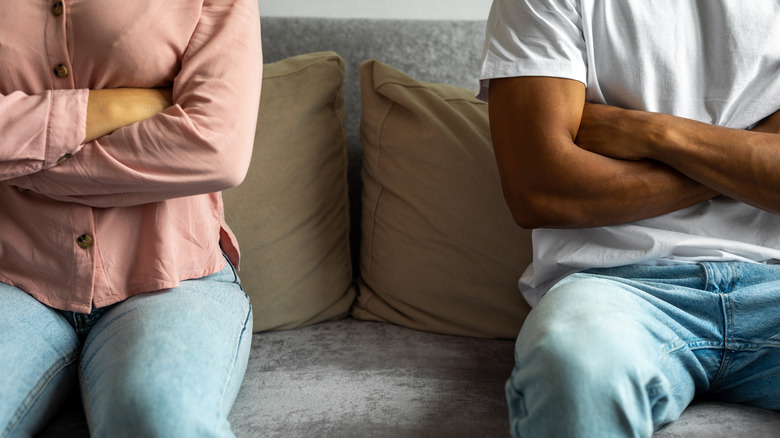 A couple sitting on a couch with crossed arms