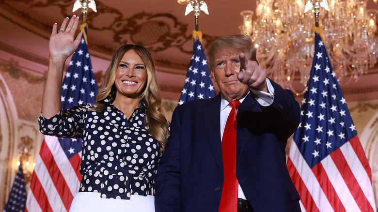 Melania Trump and Donald Trump smiling and waving at crowd