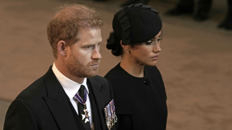 Prince Harry and Meghan Markle looking solemn