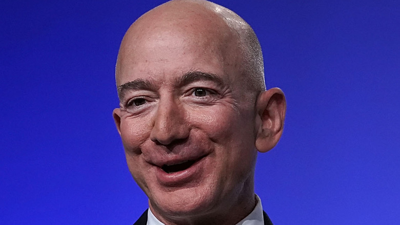 Jeff Bezos laughs in a chair