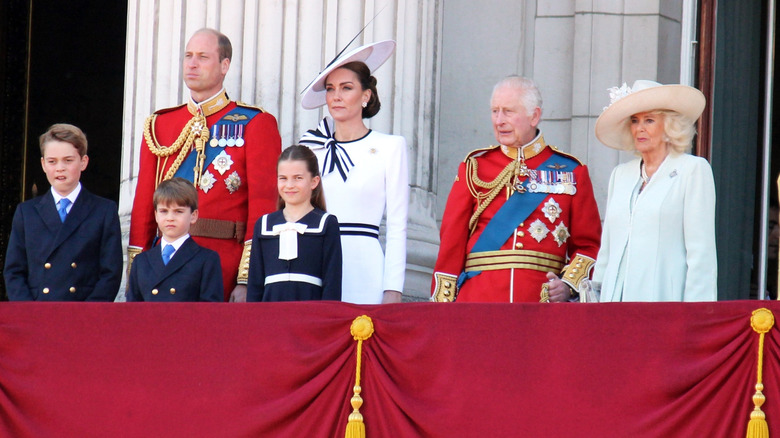 Royal family in formal dress standing on a balcony