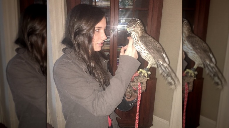 Kick Kennedy stroking a falcon she is holding on her hand.