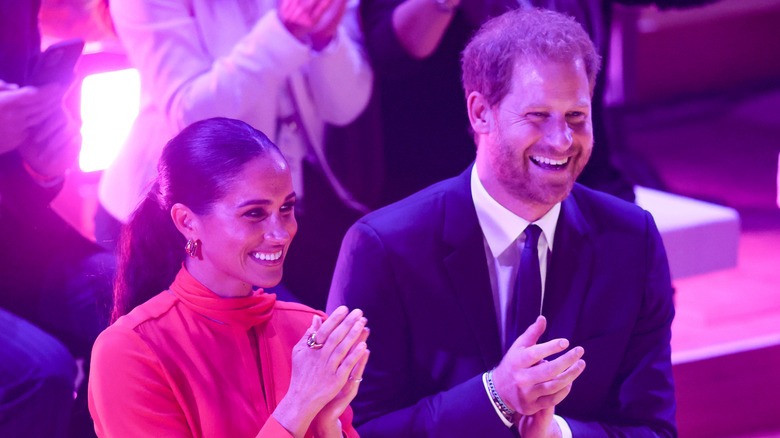 Meghan Markle and Prince Harry smiling and clapping